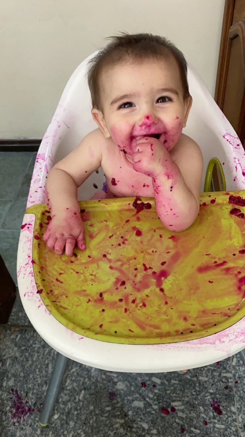Bebê sorrindo no cadeirão, lambuzado de comidinha