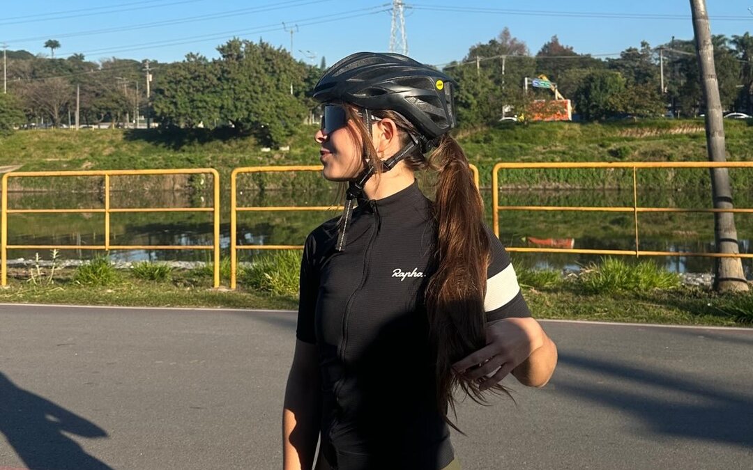 Ciclista de capacete e roupa de ciclismo ao lado da ciclovia, num dia de céu limpo